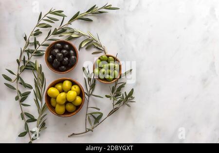 Olives vertes et noires marinées servies dans des bols avec des branches d'arbres fraîches. Alimentation méditerranéenne saine, espace pour le texte.