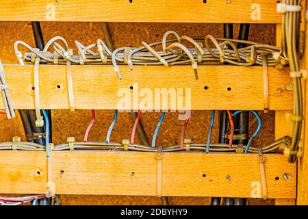 Supports en bois avec fils électriques sales blancs, rouges et bleus coupés maintenus par une attache en plastique dans une boîte de relais de commande désutilisée de l'ancien chemin de fer Rhin Banque D'Images