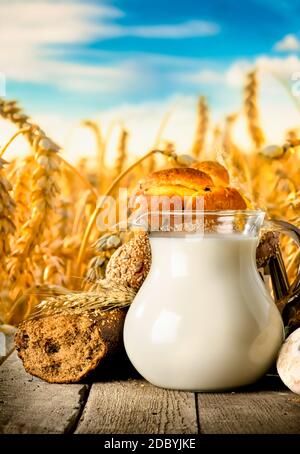 Produits laitiers et pain sur table en bois sur fond de champ Banque D'Images