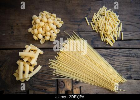 Différents types de pâtes italiennes non cuites sur un vieux brun table en bois avec une lumière de coupe et photographiée par le dessus Banque D'Images
