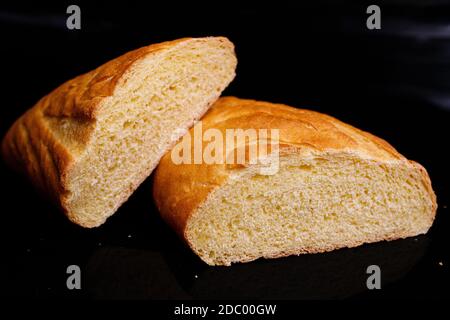 Pain blanc fait maison. Cuisson à la maison. Pain rond sur une planche de bois. Photo sur fond noir. Banque D'Images