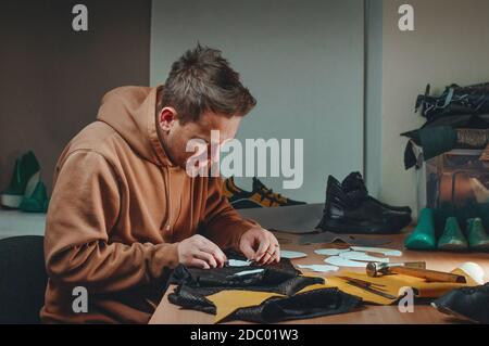 Processus de fabrication d'une sneaker par un cordonnier. Créateur de chaussures qui fait un motif en cuir. Banque D'Images