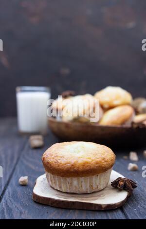 Des muffins à la cannelle et à la vanille avec garniture de noix de coco, épices et verre de lait sur une table en bois. Arrière-plan rustique. Banque D'Images