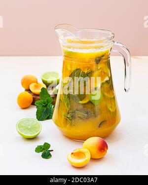 Cocktail d'abricot ou thé glacé à la menthe fraîche, au citron vert et à l'abricot. Boisson fraîche rafraîchissante en été. Arrière-plan clair. Banque D'Images