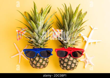 Célébrez le concept de la Journée de l'ananas d'été, vue du dessus plat de deux ananas drôles dans des lunettes de soleil avec avion modèle et étoile de mer, studio tourné isolé sur Banque D'Images