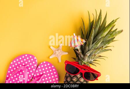 Célébrez le concept de la Journée de l'ananas d'été, vue du dessus plat de l'ananas frais drôle dans des lunettes de soleil avec l'étoile de mer et la chaussette, dans le studio isolé sur yell Banque D'Images