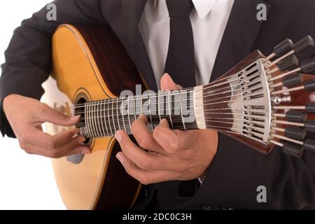 Gros plan d'un homme avec ses doigts sur les frettes d'une guitare portugaise Banque D'Images