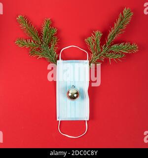 Fêtes de Noël pendant la pandémie de Covid-19. Masque chirurgical avec branches de sapin représentant un cerf. Banque D'Images