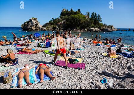 Sicile, Italie. Les touristes se rassemblent sur la plage de Spiaggia Isola Bella lors d'une chaude journée ensoleillée. Banque D'Images