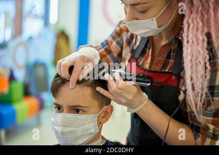 Adolescent portant un masque facial au salon de coiffure pendant une pandémie Banque D'Images