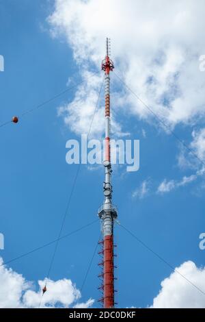 Mât de transmission contre le ciel bleu avec des nuages blancs Banque D'Images