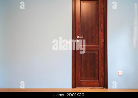 Vue frontale sur la porte en bois de la maison intérieure chambre avec parquet et murs bleus. Banque D'Images