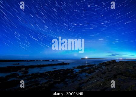 Brough du phare de Birsay sous les sentiers étoiles et faible aurora, Orkney Isles Banque D'Images