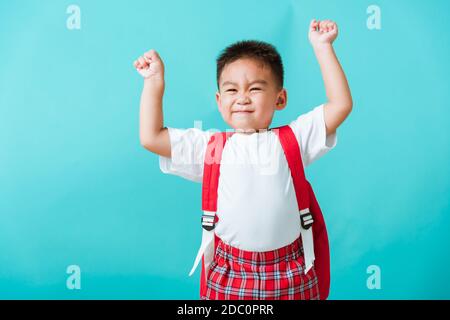 Retour à l'école. Portrait heureux asiatique mignon petit garçon d'enfant dans le sourire uniforme lever les mains vers le haut heureux quand retourner à l'école, isolé fond bleu. Enfant Banque D'Images