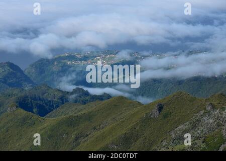 Paysage de Madère. Vue d'une montagne au-dessus des nuages jusqu'à une petite ville. Madère, Portugal. Banque D'Images
