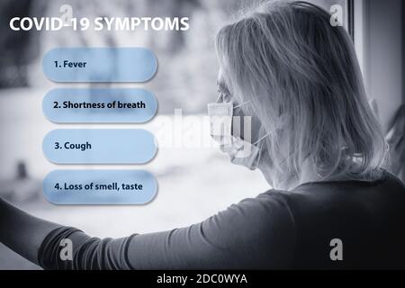 Modèle de symptômes Covid-19. La femme seule en quarantaine avec un masque protecteur jetable regarde malheureusement hors de la fenêtre. Banque D'Images