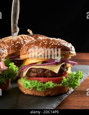 délicieux hamburgers avec côtelettes de bœuf frites, tomate, laitue et oignons, pain croustillant à la farine de blé blanc aux graines de sésame. Restauration rapide Banque D'Images