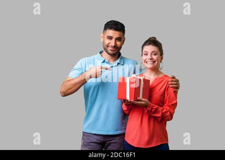 Meilleur cadeau pour elle. Portrait of happy couple dans des vêtements décontractés, man pointing at excited woman with gift box, à la satisfait et souriant à la caméra. je Banque D'Images