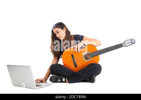 Heureuse fille posant avec la guitare et l'ordinateur portable, isolée en blanc Banque D'Images