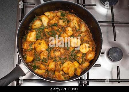 Un plat maison de Sag Aloo, un plat épicé de pommes de terre indiennes et d'épinards dans une casserole Banque D'Images