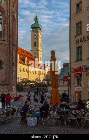 Vue sur les cafés et l'horloge de l'église Heiliggeistkirche, Munich, Bavière, Allemagne, Europe Banque D'Images