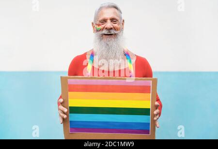 Hipster homme senior à la fierté gay tenant la bannière lgbt arc-en-ciel - Focus sur le visage Banque D'Images