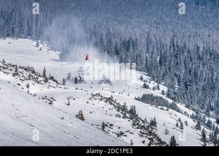 Équipage de sauvetage en hélicoptère fournissant le service dans les montagnes de High Tatra. Hélicoptère médical survolant un abri de montagne, Pologne Banque D'Images