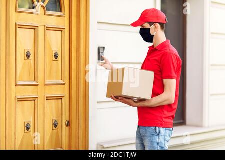 Un coursier dans un masque médical de protection avec des boîtes dans ses mains livre des colis. Prestation de services en termes de quarantaine, coronavirus pandémique Banque D'Images