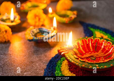 Gros plan argile allumé lumière un feu déjà sur Diya ou lampe à huile avec des fleurs sur fond de béton, Décoration de l'hindouisme rangoli, heureuse célébration profonde Banque D'Images