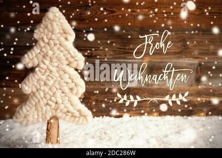 La calligraphie allemande Frohe Weihnachten signifie Joyeux Noël. Arbre de Noël en tissu blanc avec neige. Arrière-plan rustique en bois brun avec flocons de neige Banque D'Images