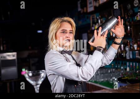 Le barman de fille mélange un cocktail dans le beerhouse Banque D'Images