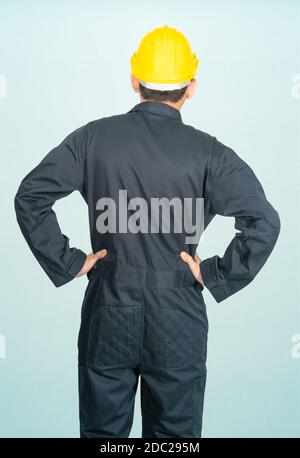 Jeune homme en combinaison casque casque casque hardhat isolé sur fond bleu Banque D'Images