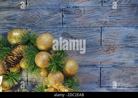 Boules de Noël jaune brillant et cône avec des écorces et des branches de pin sur fond de bois gris bleu. Carte du nouvel an Banque D'Images