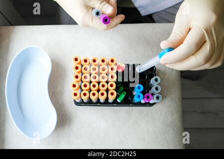 L'infirmière travaille avec des tubes à essai. Vue de dessus, gants, tubes de couleur. Banque D'Images