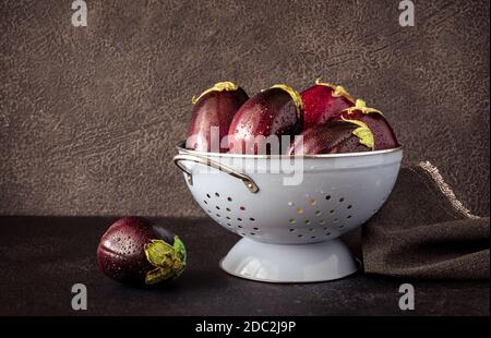 Aubergines fraîches dans la passoire sur fond noir Banque D'Images