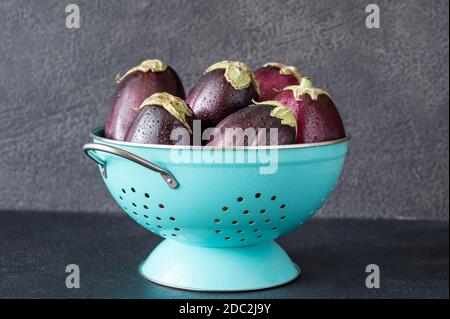 Aubergines fraîches dans la passoire sur fond noir Banque D'Images