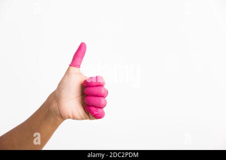Femme main portant le doigt rose lits en caoutchouc protéger aider à prévenir les empreintes digitales sur le doigt touché pièce avec le pouce vers le haut signe gestante, studio shot iso Banque D'Images