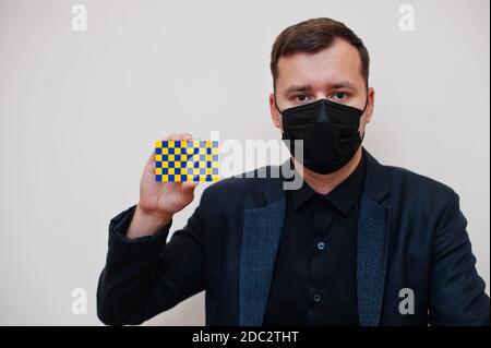 L'homme porte un masque classique noir et protège le visage, tenez la carte drapeau Surrey isolée sur fond blanc. Comtés du Royaume-Uni d'Angleterre coronavirus Covid Banque D'Images