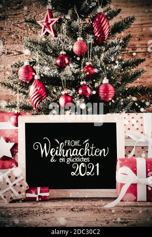 German Calligraphie Frohe Weihnachten und Ein Glueckliches 2021 signifie Joyeux Noël et UN heureux 2021. Sapin de Noël avec cadeaux, décoration boule rouge an Banque D'Images