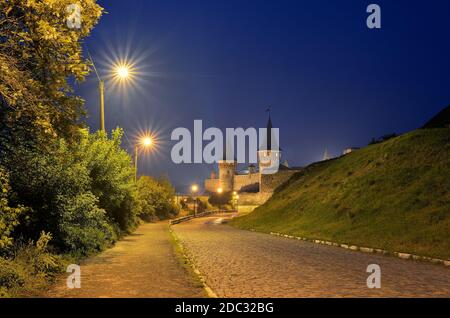 Paysage de nuit avec une route menant à l'ancienne forteresse. Feu dans la rue. Site historique. Vieille ville de Kamenetz-Podolsk, Ukraine, Europe Banque D'Images