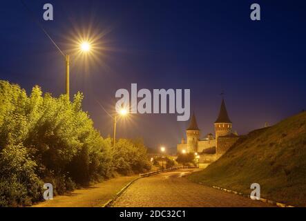 Paysage de nuit avec une route menant à l'ancienne forteresse. Feu dans la rue. Site historique. Vieille ville de Kamenetz-Podolsk, Ukraine, Europe Banque D'Images