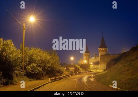 Paysage de nuit avec une route menant à l'ancienne forteresse. Feu dans la rue. Site historique. Vieille ville de Kamenetz-Podolsk, Ukraine, Europe Banque D'Images