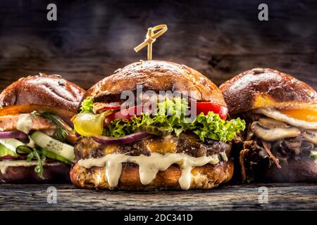 Vue de face sur trois grands hamburgers au saumon et au kebab farcis avec une salade de légumes frais et une vinaigrette Banque D'Images
