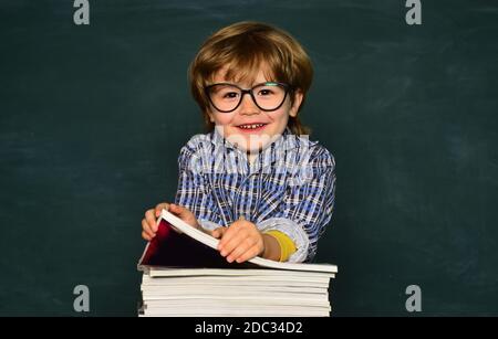 Joli garçon avec expression du visage heureux près du bureau avec fournitures scolaires. Premier jour d'école. Apprendre par un jeune enfant ou un jeune enfant. Préchoix Banque D'Images