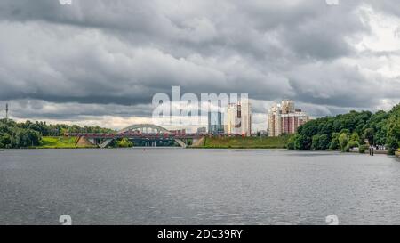 Pont de chemin de fer avec un train. De nouveaux immeubles en hauteur sur une colline verdoyante. District de Khimki, Moscou. Banque D'Images