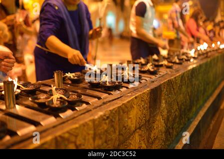 Fidèles brûler des bougies dans la pagode Shwegadon à Yangon, Myanmar (ex-Birmanie), Rangoon. La nuit, les gens dans la rangée allumer le feu. Banque D'Images