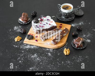Bonbons faits maison à la marmelade avec fruits et noix de dattes, bonbons orientaux sur une table noire. Banque D'Images