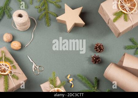 Cadre, bordure faite de boîtes, papier artisanal, ficelle, ciseaux, oranges séchées et décor naturel pour l'emballage DE NOËL, cadeaux du nouvel an sur fond vert. Co Banque D'Images