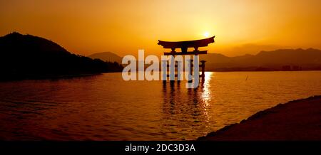 Orange Miyajima Grande porte de Torii au coucher du soleil dans la baie d'Hiroshima, dans l'ouest du Japon. Banque D'Images