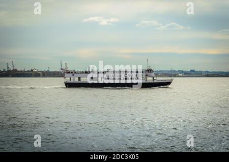 Un bateau de croisière rempli de touristes sur son chemin à la Statue de la liberté. New York City, NY/USA Banque D'Images